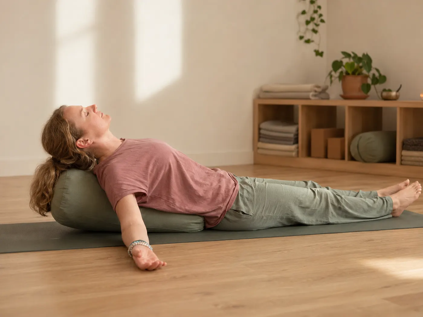 Vrouw ligt ontspannen achterover over een bolster in een ondersteunde vishouding